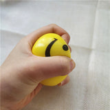 Main pressant la Balle anti-stress Smiley jaune, illustrant la déformation sous l’effet de la pression