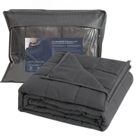 Couverture lestée 4 kg gris foncé pliée avec sa housse de rangement transparente et les informations produit.