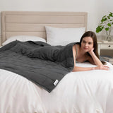 Couverture lestée 4 kg gris foncé utilisée sur un lit pour favoriser la relaxation et le calme.
