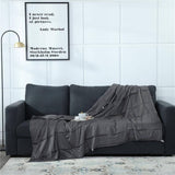 Couverture lestée gris foncé élégamment disposée sur un canapé, parfaite pour un moment de relaxation