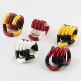 Cinq tortillons multicolores (rouge, jaune, blanc et noir) enroulés en spirale pour la manipulation sensorielle
